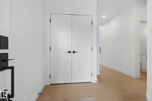 Entryway featuring light wood-finish flooring, white walls, and a pair of white doors with matte black hardware - 105 Wyatt Ridge, Fort Saskatchewan, AB 