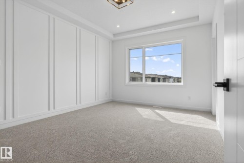 Spacious room featuring a decorative accent wall with vertical panel molding, recessed lighting, and a contemporary ceiling fixture - 105 Wyatt Ridge, Fort Saskatchewan, AB 