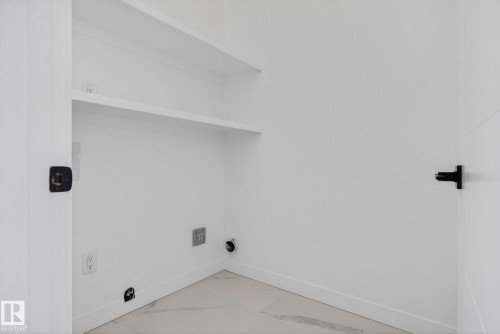 Dedicated laundry area featuring white walls, two built-in storage shelves, and light-toned flooring - 105 Wyatt Ridge, Fort Saskatchewan, AB 