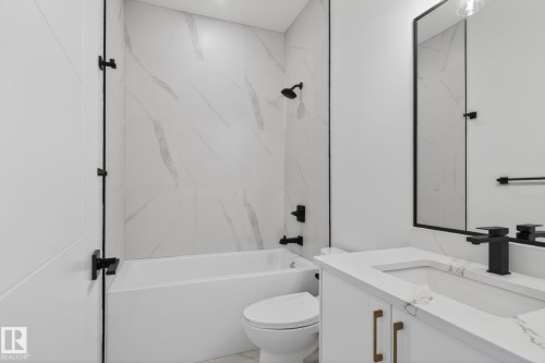 Modern bathroom featuring a white vanity with integrated sink, a large framed mirror, and a combination tub/shower with matte black fixtures - 105 Wyatt Ridge, Fort Saskatchewan, AB 