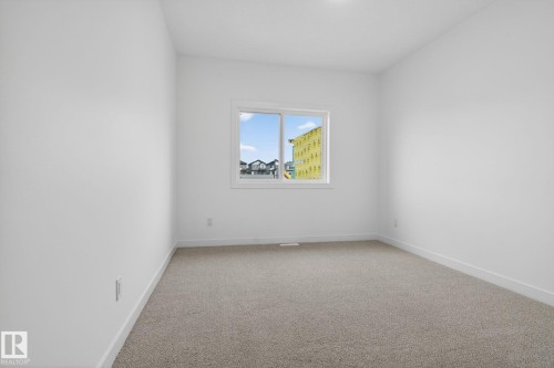 Bright room featuring a window with white trim, neutral carpeting, white walls, and white baseboards - 105 Wyatt Ridge, Fort Saskatchewan, AB 