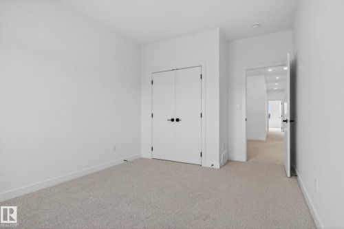 Carpeted room featuring white walls, white trim, and a double-door closet with black hardware - 105 Wyatt Ridge, Fort Saskatchewan, AB 