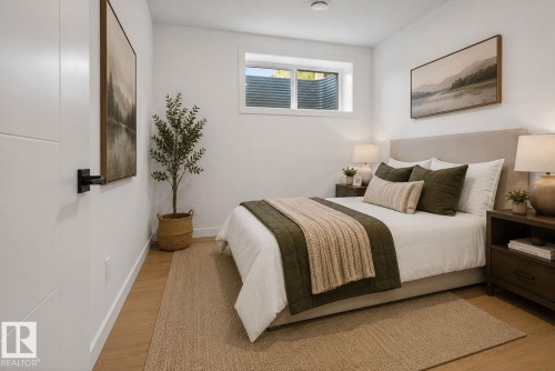 Bedroom featuring an egress window, light wood-finish flooring, white baseboards, and a contemporary flat panel door with matte black hardware - 105 Wyatt Ridge, Fort Saskatchewan, AB 