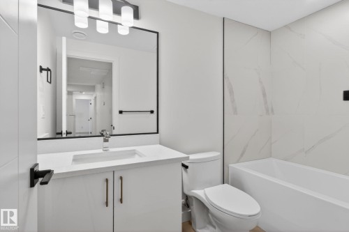 Contemporary bathroom featuring a white vanity with integrated sink, quartz-finish countertop, and matte black hardware - 105 Wyatt Ridge, Fort Saskatchewan, AB 