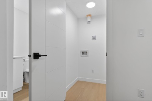 Laundry area featuring light wood-finish flooring, white walls, and a ceiling-mounted light fixture - 105 Wyatt Ridge, Fort Saskatchewan, AB 