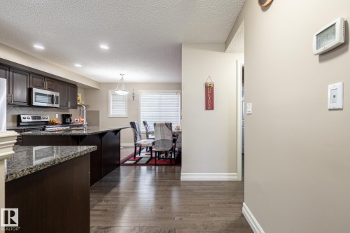 Kitchen featuring dark wood cabinetry, stainless steel appliances, and stone countertops - 59 655 Tamarack Road, Edmonton, AB 