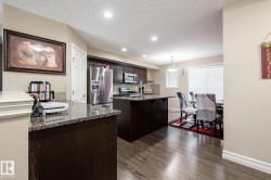 Kitchen and dining area featuring dark wood-finish cabinetry, stainless steel appliances, granite countertops, and wood-finish flooring - 