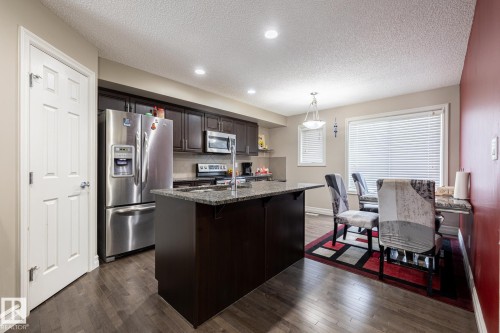 Kitchen and dining area featuring wood-finish flooring, recessed lighting, and a kitchen island with a stone-finish countertop - 59 655 Tamarack Road, Edmonton, AB 