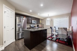 Kitchen and dining area featuring wood-finish flooring, recessed lighting, and a kitchen island with a stone-finish countertop - 
