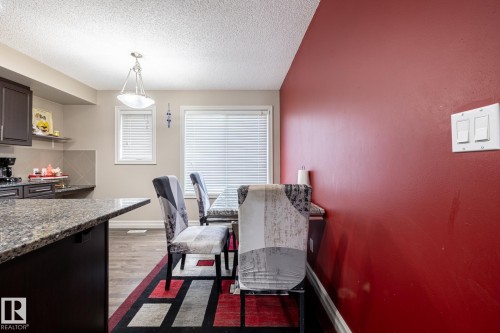 Kitchen and dining area featuring dark wood-finish cabinetry, a granite-style countertop, and wood-finish flooring - 59 655 Tamarack Road, Edmonton, AB 