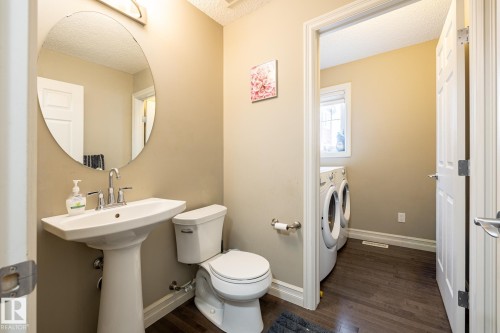 Pedestal sink with chrome faucet, complemented by a round wall-mounted mirror - 59 655 Tamarack Road, Edmonton, AB 
