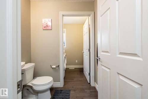Bathroom with a white toilet, light beige wall paint, and a white six-panel door - 59 655 Tamarack Road, Edmonton, AB 