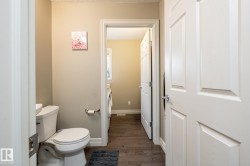 Bathroom with a white toilet, light beige wall paint, and a white six-panel door - 