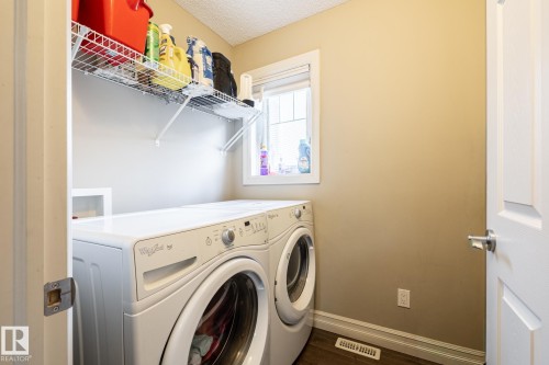 Dedicated laundry area featuring a window, built-in wire shelving, wood-finish flooring, and light neutral wall paint - 59 655 Tamarack Road, Edmonton, AB 