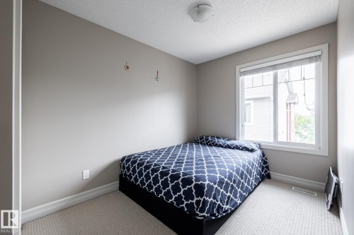 Carpeted room featuring a white-trimmed window, neutral wall paint, white baseboards, and a ceiling-mounted light fixture - 59 655 Tamarack Road, Edmonton, AB 