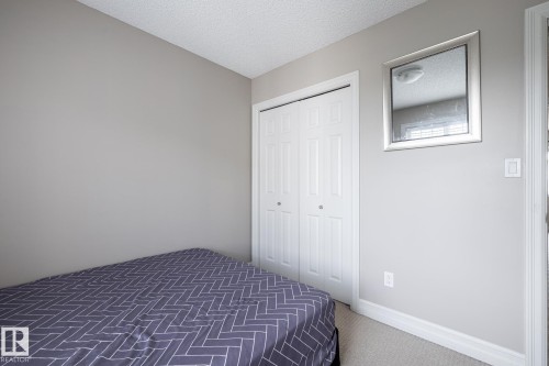 Neutral-toned room featuring a bifold closet, light gray walls, white baseboards, and a textured ceiling - 59 655 Tamarack Road, Edmonton, AB 