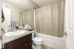 Bathroom featuring a dark wood-finish vanity with a single basin sink, speckle-patterned countertop, and an integrated shower-tub combination - 