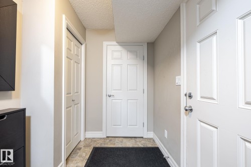 Entryway featuring panel doors, neutral wall paint, and a textured ceiling - 59 655 Tamarack Road, Edmonton, AB 