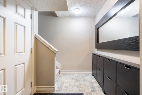 Foyer featuring paneled door, gray wall tones, and tiled flooring - 59 655 Tamarack Road, Edmonton, AB 