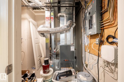Utility area featuring a furnace unit, exposed ductwork, electrical panel, and electrical wiring on a wood-paneled wall - 59 655 Tamarack Road, Edmonton, AB 