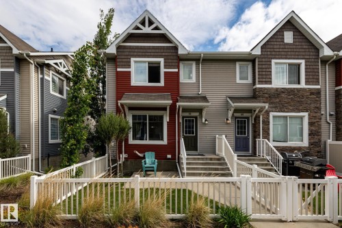 Townhome exterior featuring varied siding materials including red and gray horizontal siding, dark brown shingles, and a stone facade accent - 59 655 Tamarack Road, Edmonton, AB 