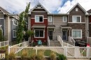 Townhome exterior featuring varied siding materials including red and gray horizontal siding, dark brown shingles, and a stone facade accent - 59 655 Tamarack Road, Edmonton, AB 