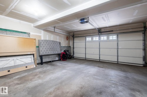 Attached garage featuring a concrete floor, an automatic garage door opener, and a garage door with upper window inserts - 59 655 Tamarack Road, Edmonton, AB 