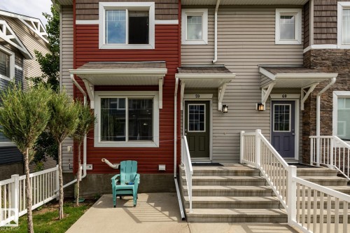 Exterior facade featuring red and beige horizontal siding with stone accents - 59 655 Tamarack Road, Edmonton, AB 