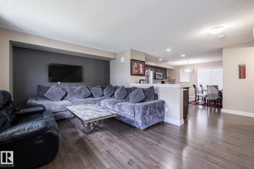Open-concept living area featuring wood-finish flooring, a contemporary accent wall, and recessed lighting - 59 655 Tamarack Road, Edmonton, AB 