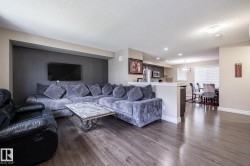 Open-concept living area featuring wood-finish flooring, a contemporary accent wall, and recessed lighting - 