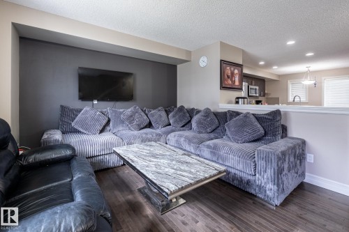 Open concept living space featuring wood-finish flooring, recessed lighting, and a partial wall separating the kitchen area - 59 655 Tamarack Road, Edmonton, AB 