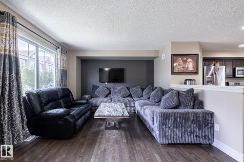 Open-concept living area featuring wood-finish flooring, a neutral color palette, and a large window - 59 655 Tamarack Road, Edmonton, AB 