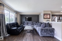 Open-concept living area featuring wood-finish flooring, a neutral color palette, and a large window - 