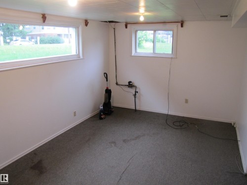 Finished interior space featuring two windows, neutral wall paint, and gray carpeting - 8122 83 Avenue, Edmonton, AB 