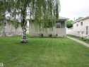 Stucco exterior with a covered front porch, an established front lawn, a mature birch tree, and a concrete walkway - 8122 83 Avenue, Edmonton, AB 