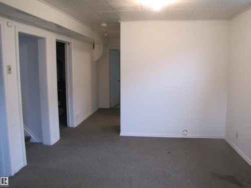Carpeted room with white painted walls and a dropped ceiling - 8122 83 Avenue, Edmonton, AB 