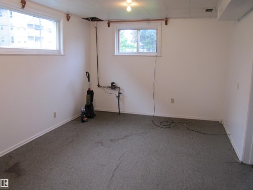 Carpeted room featuring white walls and two windows - 8122 83 Avenue, Edmonton, AB 