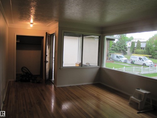 Hardwood flooring throughout, featuring a bay window, crown molding, and a solid wood entry door - 8122 83 Avenue, Edmonton, AB 
