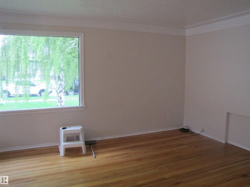 Refinished wood-finish flooring, crisp white baseboards, and neutral wall tones - 8122 83 Avenue, Edmonton, AB 