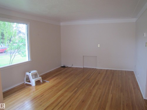Hardwood flooring throughout a room with white baseboards and crown molding - 8122 83 Avenue, Edmonton, AB 