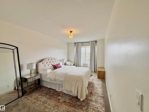 Carpeted room featuring a window with drapes, a central ceiling light fixture, and light-colored walls - 5281 Edgemont Boulevard, Edmonton, AB 