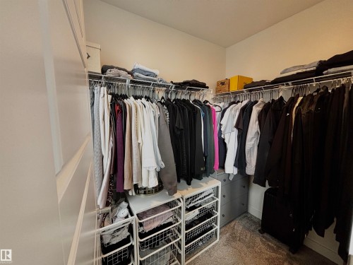 Walk-in closet featuring built-in wire shelving, multiple hanging rods, and a gray carpeted floor - 5281 Edgemont Boulevard, Edmonton, AB 