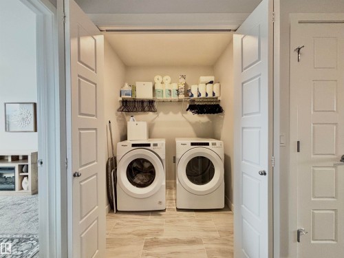 Dedicated laundry alcove featuring tile flooring, built-in wire shelving, and overhead lighting - 5281 Edgemont Boulevard, Edmonton, AB 