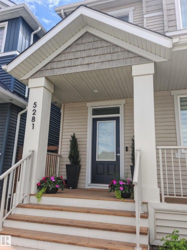 Covered porch entry featuring wood-finish steps and white railings - 5281 Edgemont Boulevard, Edmonton, AB 