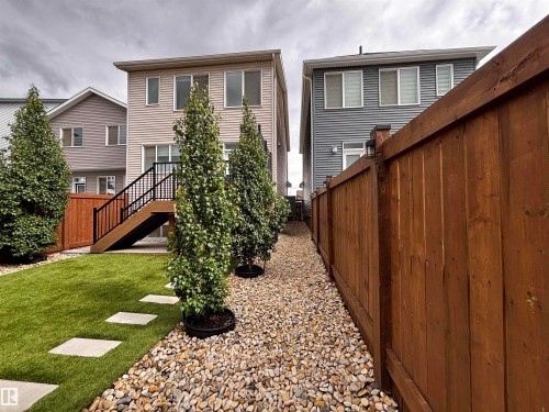 Private backyard featuring a well-maintained lawn, stepping stones, ornamental trees, and a gravel path - 5281 Edgemont Boulevard, Edmonton, AB 