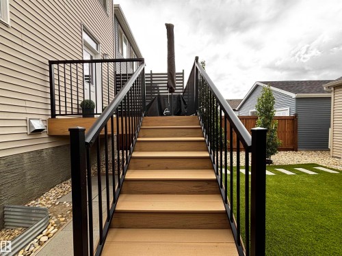 Composite deck stairs with black metal railings leading to an upper deck area - 5281 Edgemont Boulevard, Edmonton, AB 