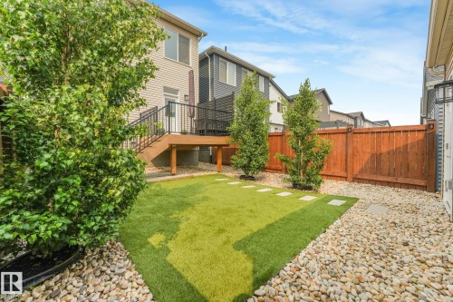 Expansive backyard featuring a manicured artificial lawn, decorative river rock landscaping, and mature trees - 5281 Edgemont Boulevard Nw, Edmonton, AB - Outdoor With Deck Patio Veranda