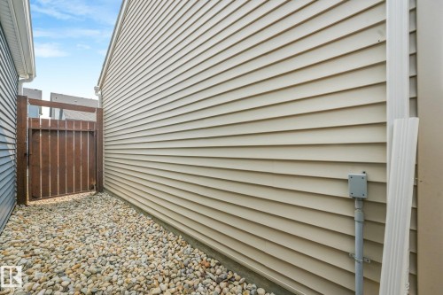 Side yard featuring a wooden gate and river rock ground cover - 5281 Edgemont Boulevard Nw, Edmonton, AB - Outdoor With Exterior