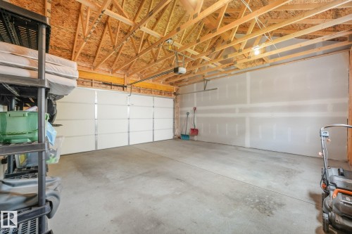 Spacious two-car garage featuring a concrete floor, exposed wood ceiling trusses, and an automatic overhead door - 5281 Edgemont Boulevard Nw, Edmonton, AB - Indoor Photo Showing Garage