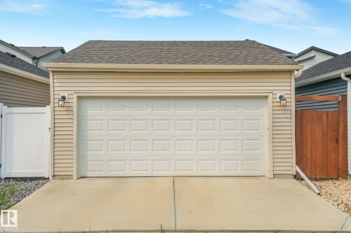 Detached garage featuring light-colored siding, a panel-style overhead door, and a shingle roof - 5281 Edgemont Boulevard Nw, Edmonton, AB - Outdoor